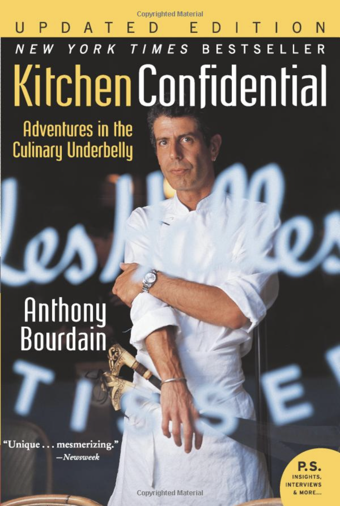 the “updated edition” paperback cover of Kitchen Confidential by Anthony Bourdain, featuring a younger Bourdain in chef’s whites and an apron looking through the window of Les Halles, the restraunt he worked at when he wrote it