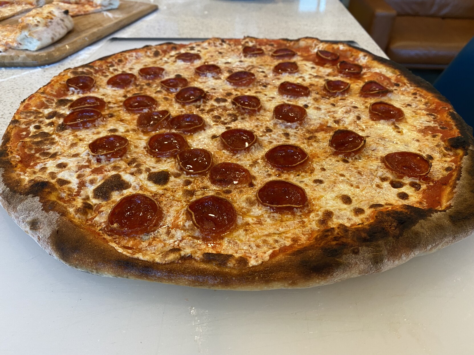 Large, round peperoni pizza home-fired in a gas ooni koda, well leopard spotted mozza, cupped pepperonis, perfectly charred and shaped crust (ok, the bit around 2 o’clock around is actually burned)under baked bottom on account of experimenting w/ both a pizza-ring and a lower (~550F) launch temperature while fucking up and using too much cheese and sauce