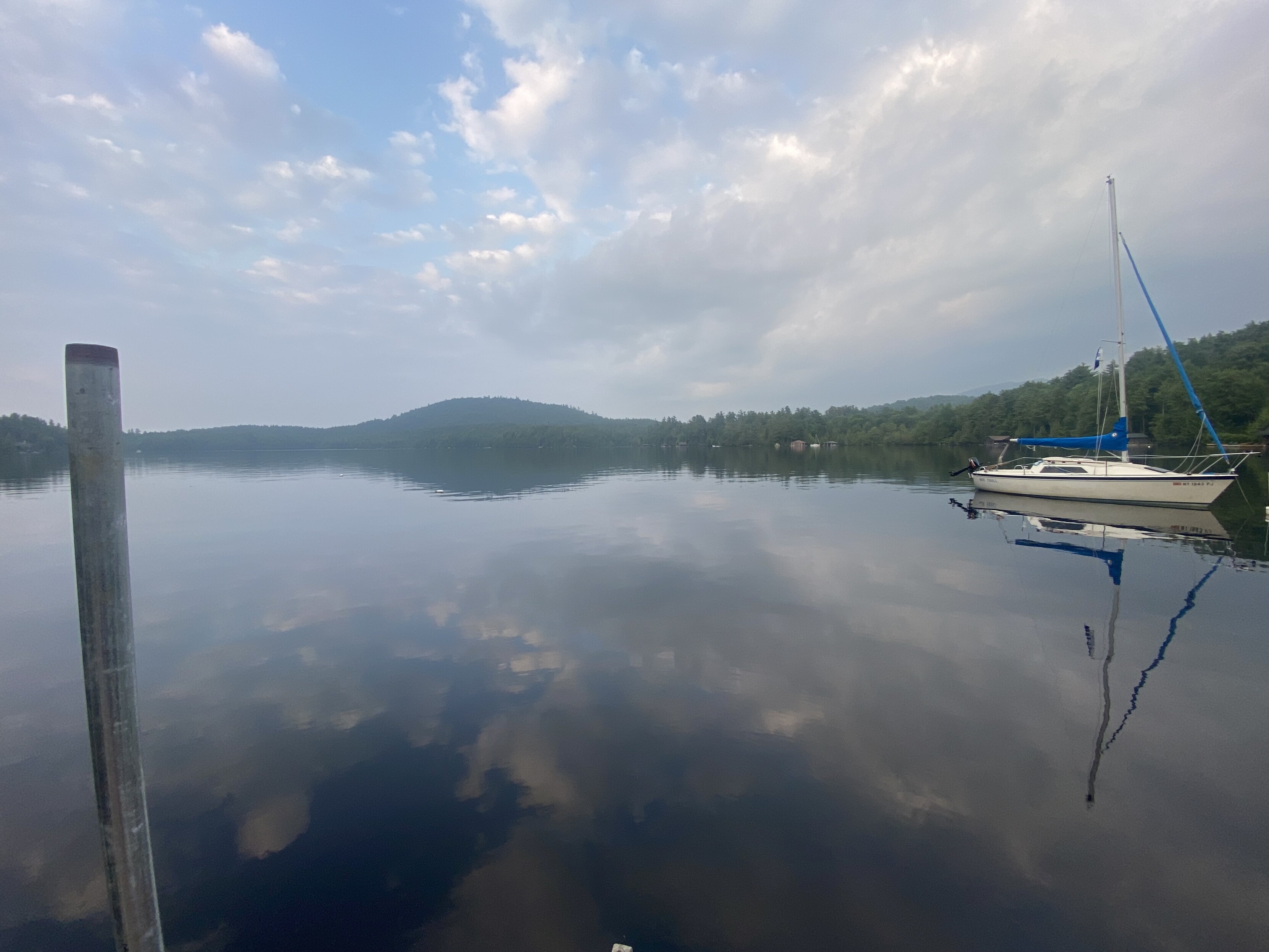 upper saranac lake, 150 aqi, a small sail boat named "She Troll" anchored in the right foreground