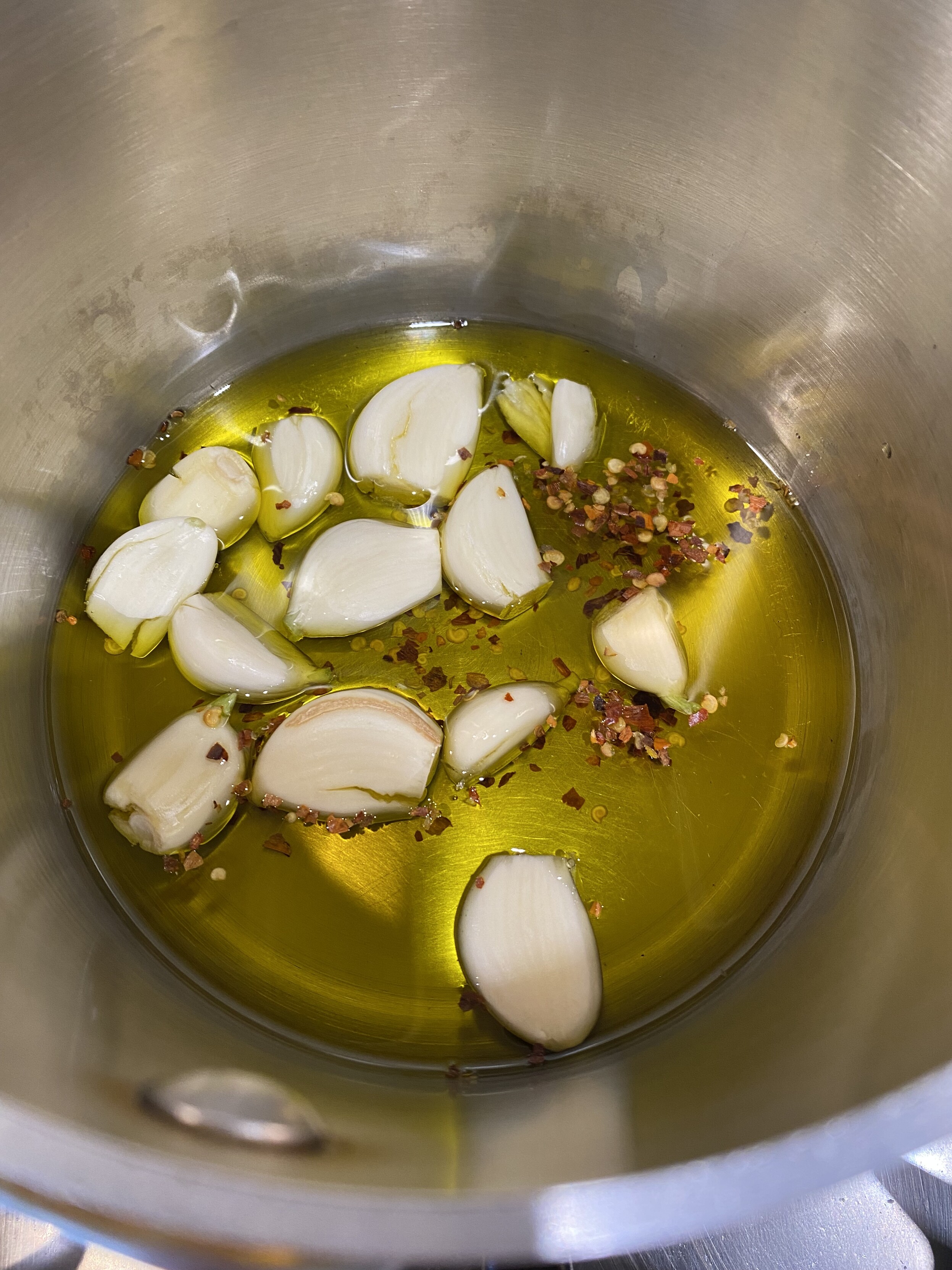 the half with a head of garlic, large pinches of red pepper flakes, and soon (missing), four full stalks of basil in a small sauce pan