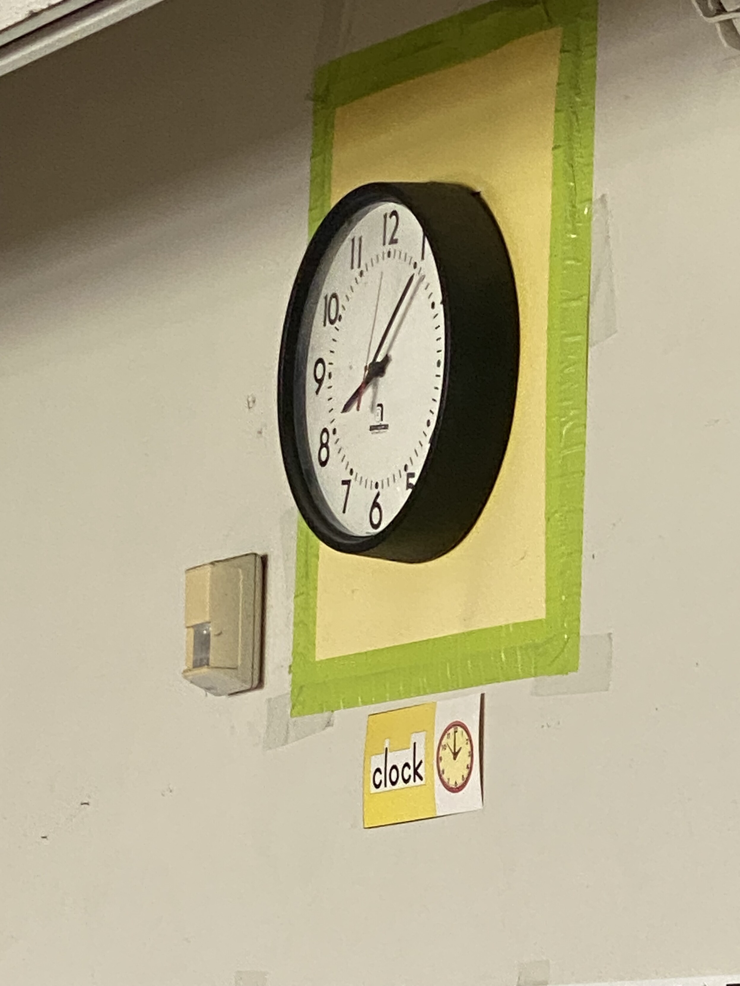 photograph of the clock high up on the wall in a public school classroom