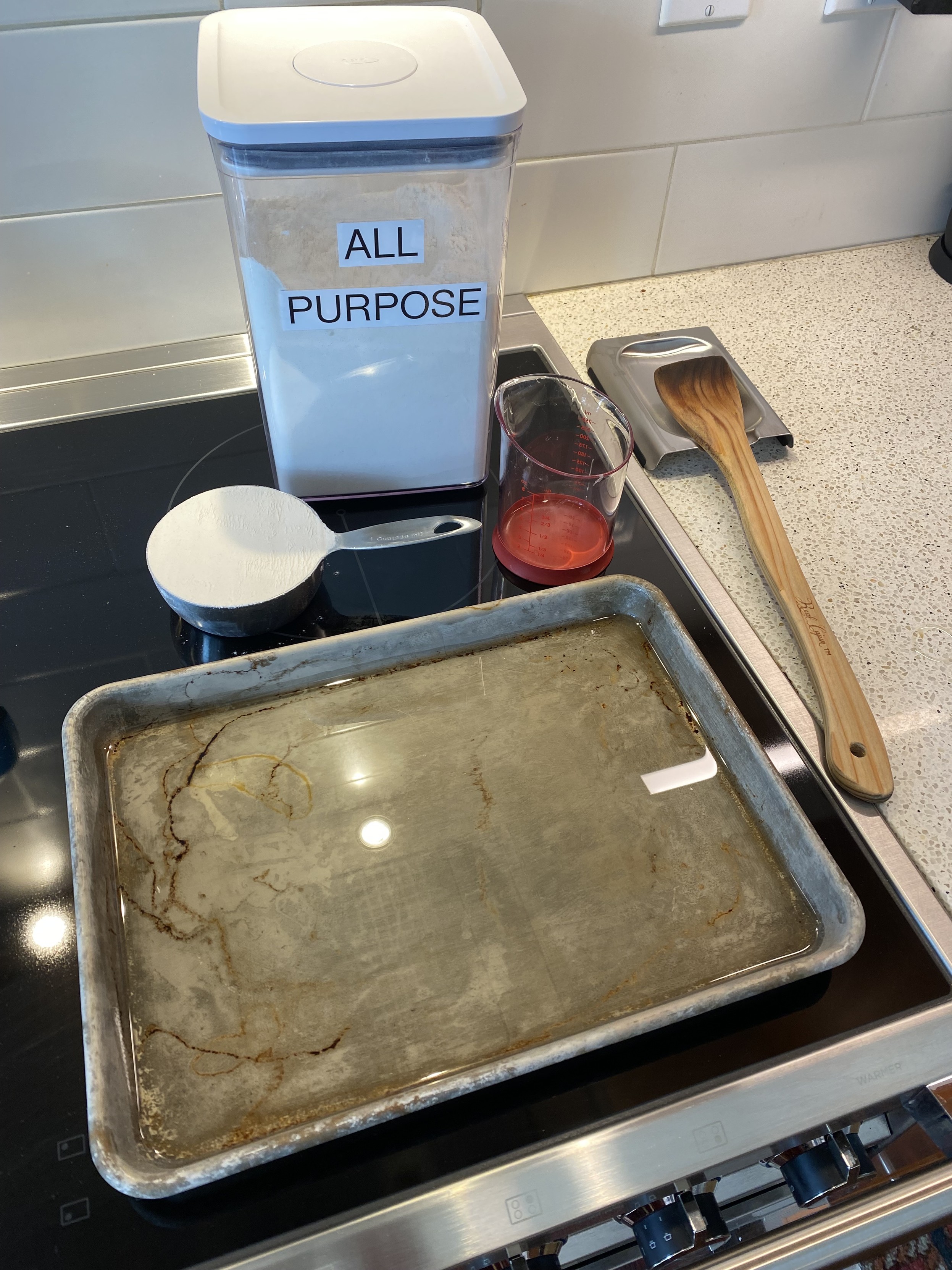 a quarter sheet with a cup of oil in it, a cup of all purpose flour and roux spoon standing by, about to be addedmethod and recipe from serious eats, as per, which i use now instead of the old note card i used to dig out