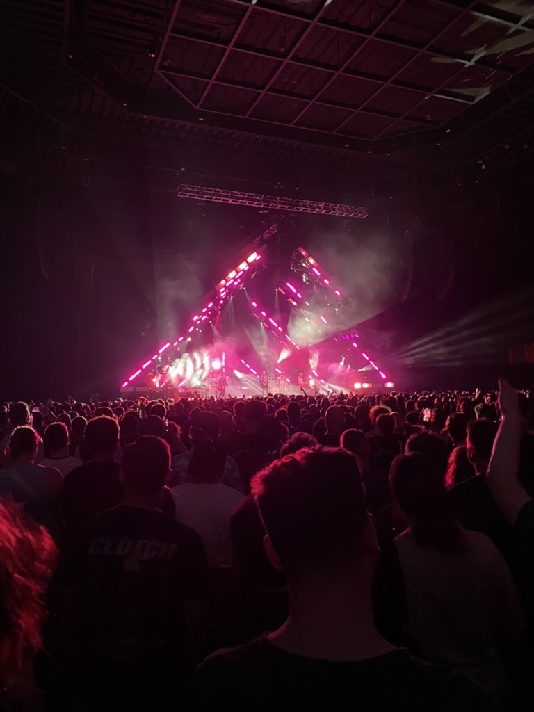 audience photo of Queens of the Stone Age performing at Bill Graham Auditorium, the band is lit by a triangle of pink lights overhead hard to believe, I’m sure, but with a crowd of mostly 40-something couples in black rock t-shirts (yours truly included), the damned bar ran out of IPA before the band even started