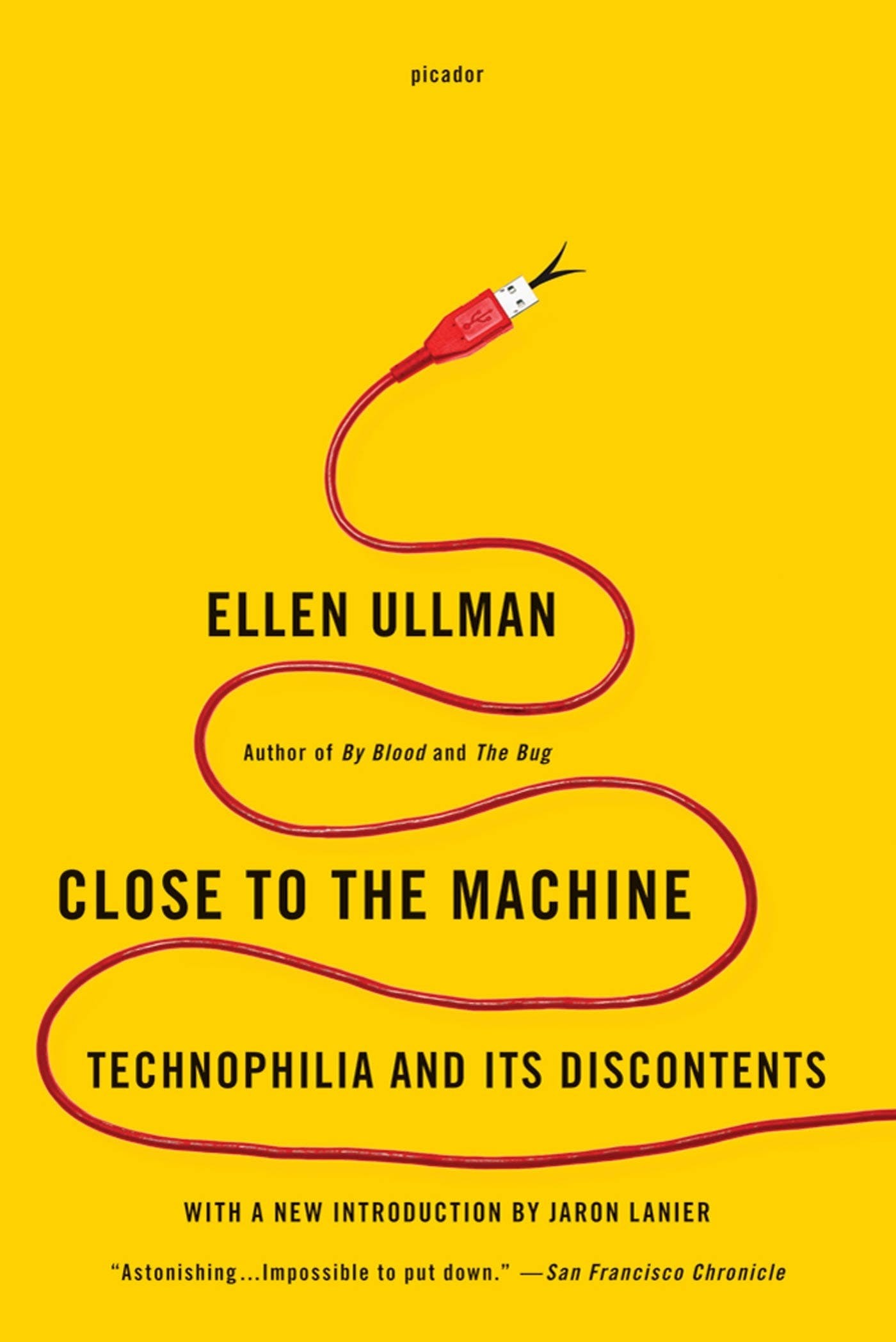 The paperback cover of “Close to the Machine” by Ellen Ullman, author’s over title over subtitle in black sans caps on a flat yellow background with a red USB-A cable serpents up from the bottom right corner to the top center. a black snake’s tongue flicks out from the USB cable connector.