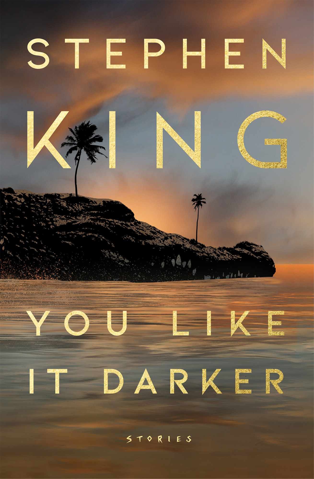 The hardback cover of “You Like it Darker” by Stephen King, as I read it. Author name over title in a pale yellow all-caps futura variant with a few pointed descenders and an interesting capital K specifically (more like a leaning V with a tail stollen from the letter Q?) over a photograph of an island with two palm trees in dark browns and blues.