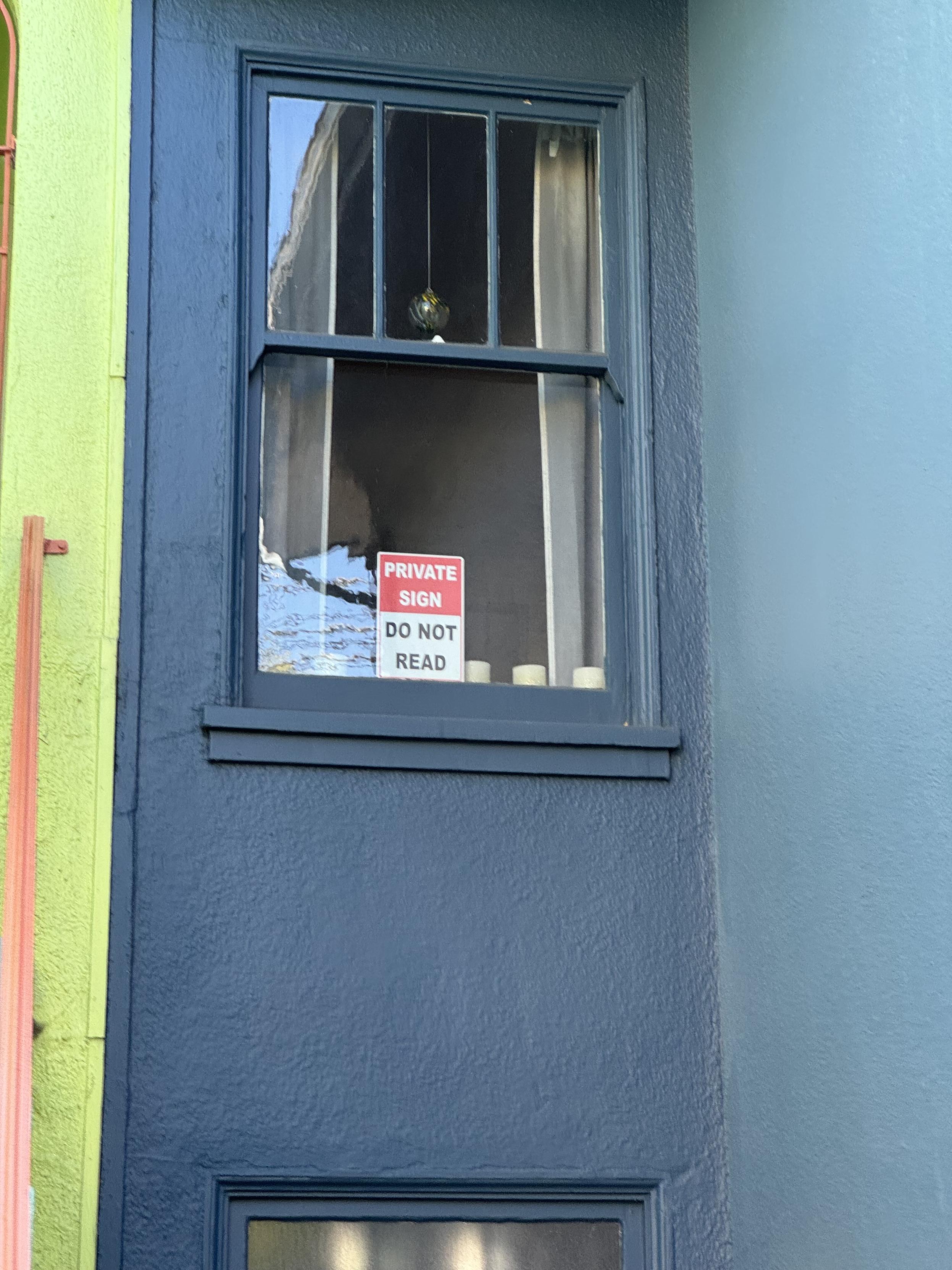 A fake road sign in the window of a house in san francisco that says:PRIVATESIGNDO NOTREADI'm sure on the backside, it didn't say nothing, etc., etc.