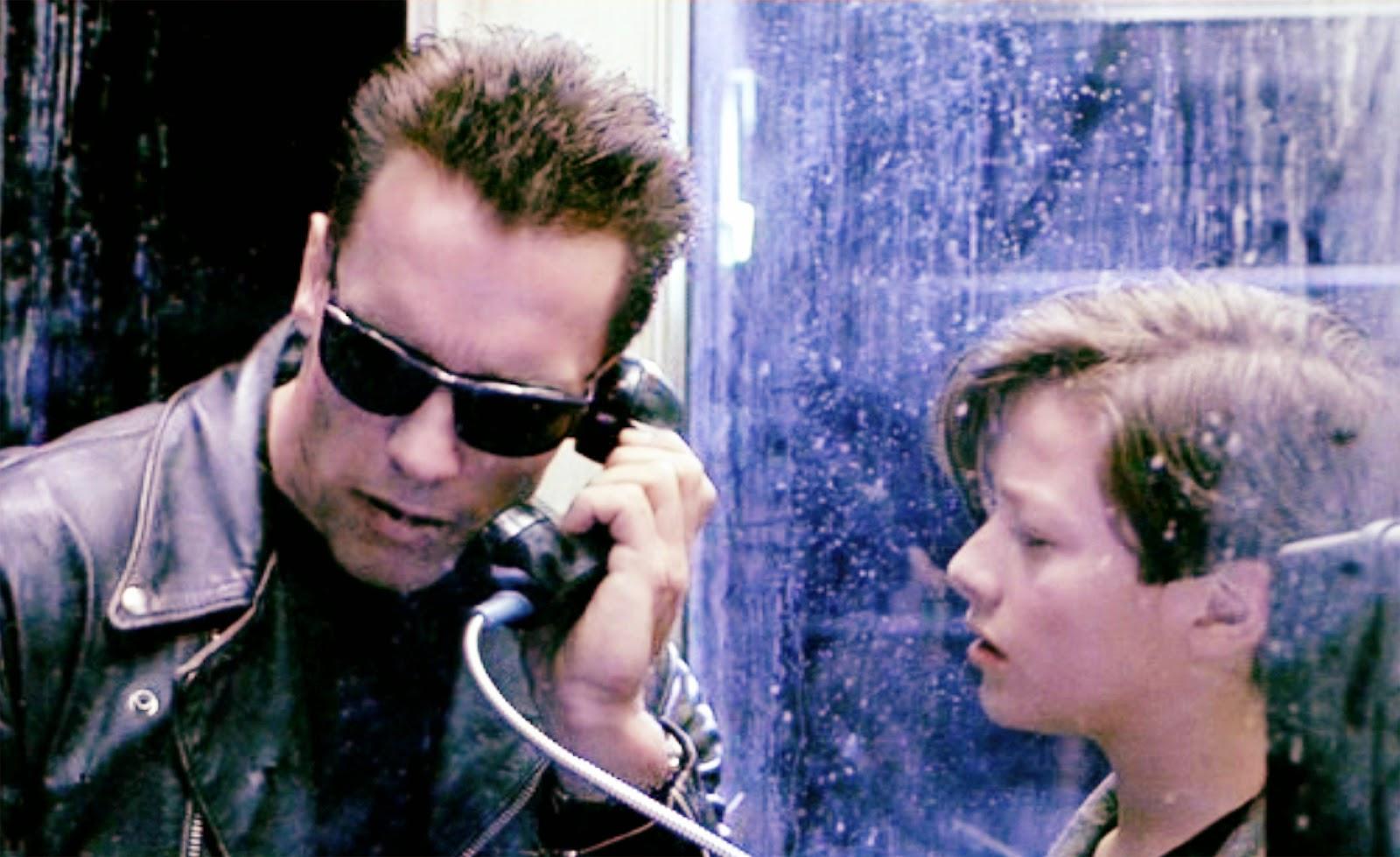 a screenshot from Terminator 2 of the T100 on the left and a young John Connor on the right. The T100 is on a pay phone talking to the T1000 at John Connor’s house, tricking the T1000 into admitting that it is not actually John’s foster-parent by asking after John’s dog but using the wrong name for itTERMINATOR           (in John's voice)      I'm right here.  I'm fine.           (to John, a whisper)      What's the dog's name?                 JOHNMax.Terminator nods. Speaks into the phone.TERMINATORHey, Janelle, what's wrong with Wolfy? I can      hear him barking.  Is he okay?                 JANELLE           (filtered)      Wolfy's fine, honey.  Where are you?Terminator unceremoniously hangs up the phone.Turns to John.TERMINATORYour foster parents are dead. Let's go.Terminator heads for the bike. John, shocked, stares after him.[pushing up glasses] This scene gets a lot of meme time but it’s also pretty funny because you would think the dumb ol’ T1000 would have been loaded with a pretty extensive dossier on John Connor that included the dog’s name. 