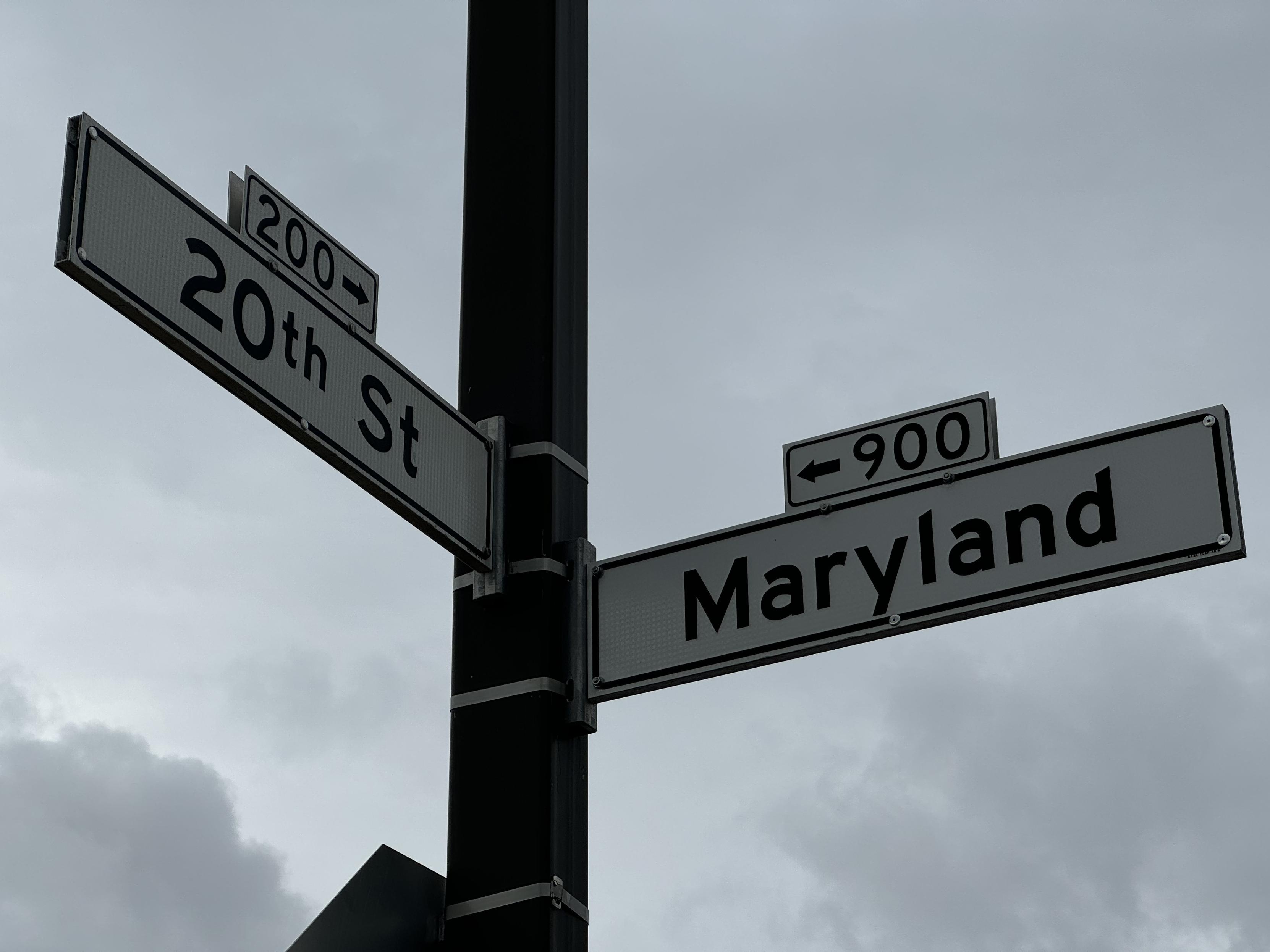 photograph looking up at the street signs on the corner of 20th street and Maryland street on a gray cloudy day 