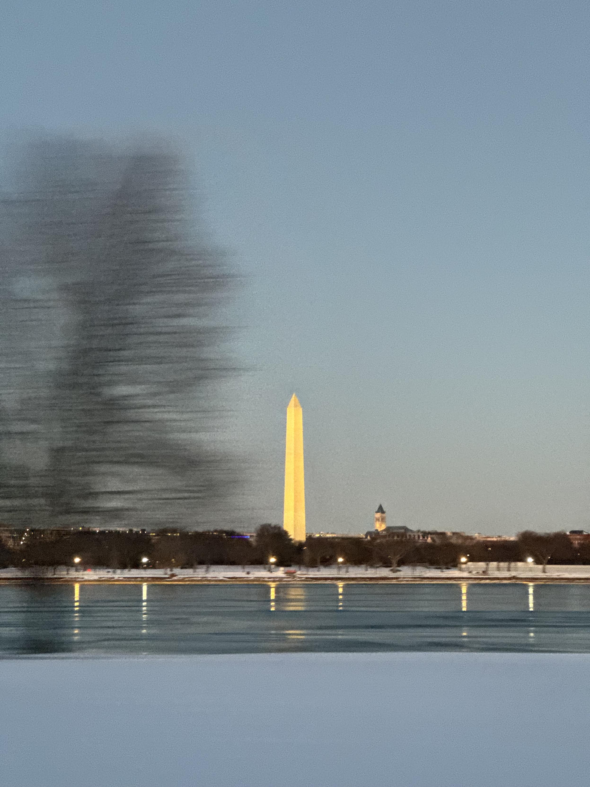 Photograph taken from a moving taxi of the Washington Monument as seen from a bridge over the Potomac River in Washington, DC.