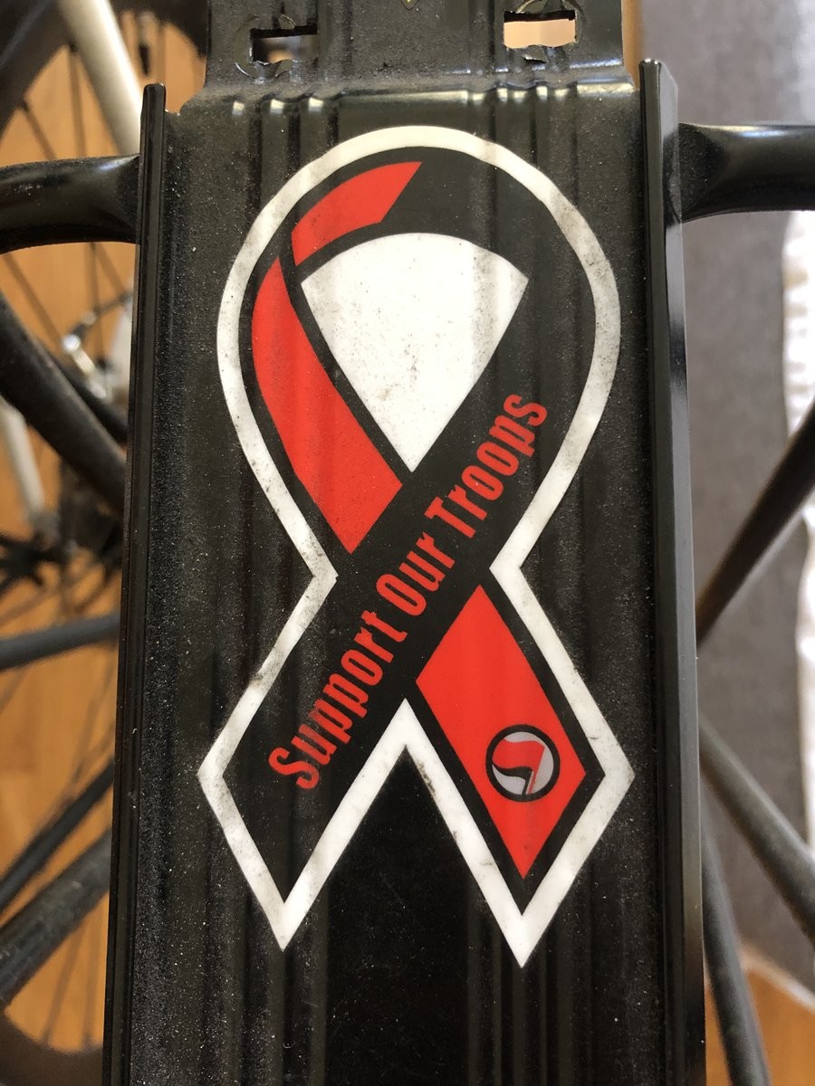 rear bike rack with a black and red “support our troops” ribbon sticker on it