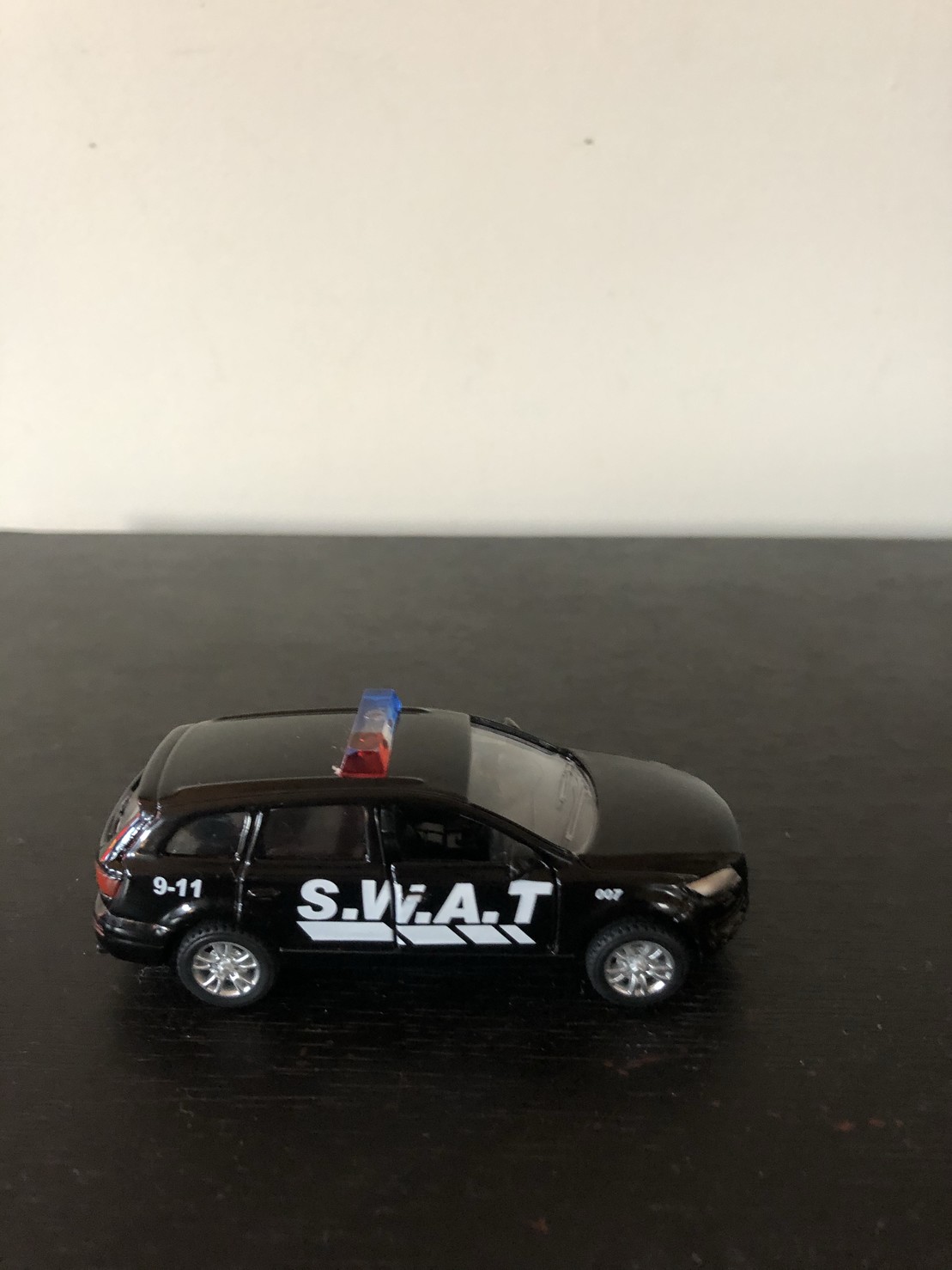 matchbox car sized black toy S.W.A.T. SUV that say to call 9-1-1 on it